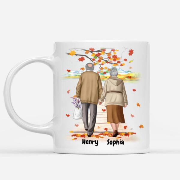 White ceramic coffee mug featuring a personalized illustration of an elderly couple walking hand in hand under autumn leaves, symbolizing lifelong love and companionship. Customizable with names, making it a perfect sentimental gift for grandparents, anniversaries, or special occasions. Microwave and dishwasher safe. Order now!