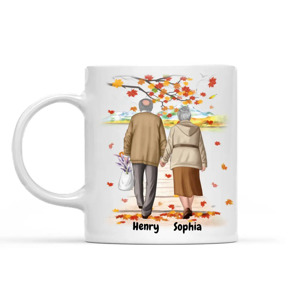 White ceramic personalized coffee mug featuring a custom illustration of an elderly couple walking hand in hand under autumn leaves, with names "Henry" and "Sophia" printed below. A perfect sentimental gift for grandparents, anniversaries, or special occasions. Dishwasher and microwave safe. Order now!
