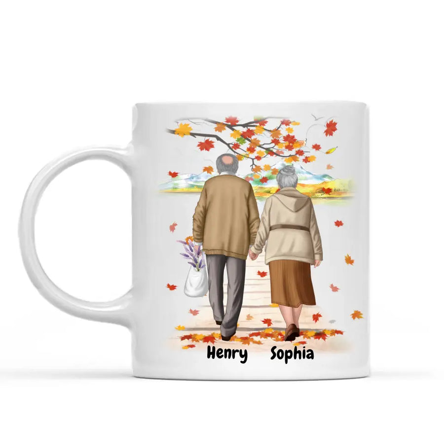 White ceramic personalized coffee mug featuring a custom illustration of an elderly couple walking hand in hand under autumn leaves, with names "Henry" and "Sophia" printed below. A perfect sentimental gift for grandparents, anniversaries, or special occasions. Dishwasher and microwave safe. Order now!